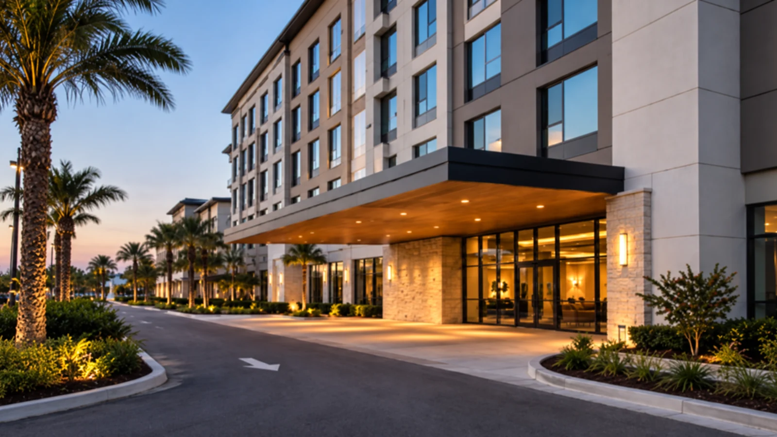 Modern multi-story hotel with a landscaped guest-arrival drive at dusk.